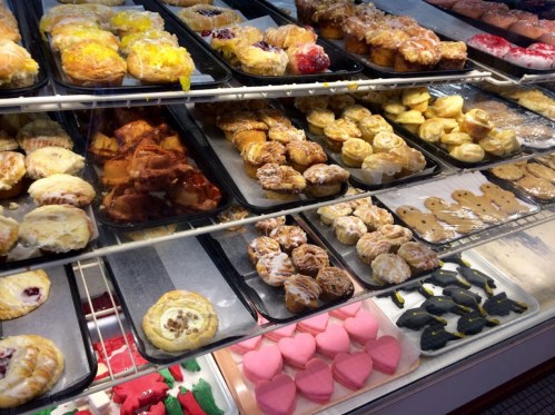 A display case filled with various baked goods, including pastries, cookies, and colorful desserts.