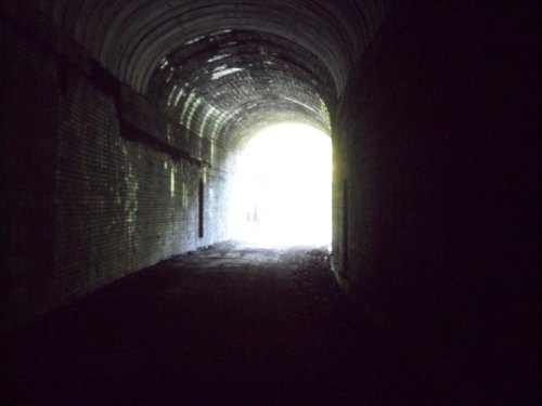 A dark tunnel with brick walls, leading to a bright light at the far end.