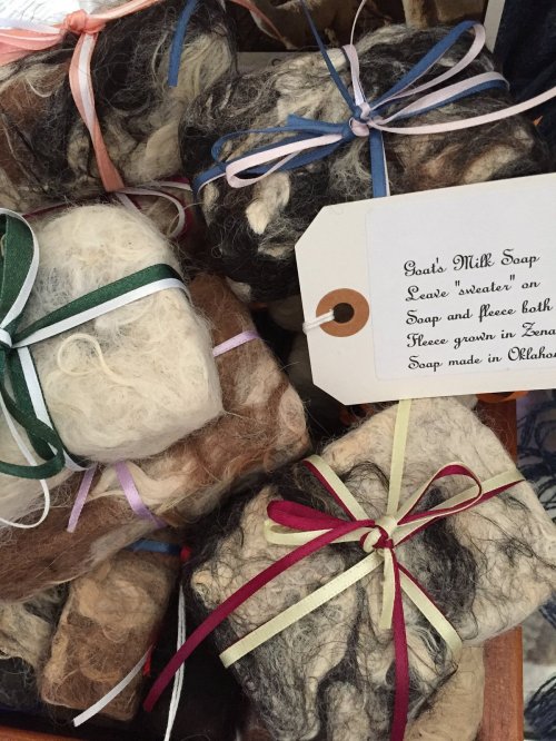 A collection of handmade goat's milk soap bars wrapped in colorful ribbons, with a tag describing the product.