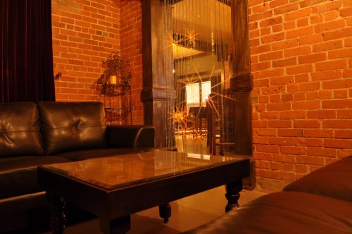Cozy lounge area with leather sofas, a glass coffee table, and exposed brick walls, creating a warm atmosphere.