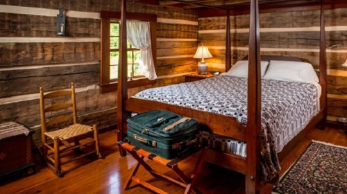 Cozy log cabin bedroom featuring a four-poster bed, wooden furniture, and warm lighting.