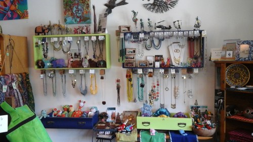 Colorful display of jewelry and crafts on shelves, featuring necklaces, figurines, and various decorative items.