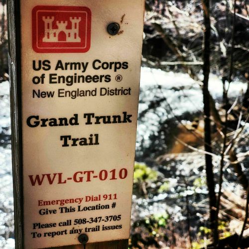 Sign for Grand Trunk Trail by the US Army Corps of Engineers, with emergency contact information and a scenic background.