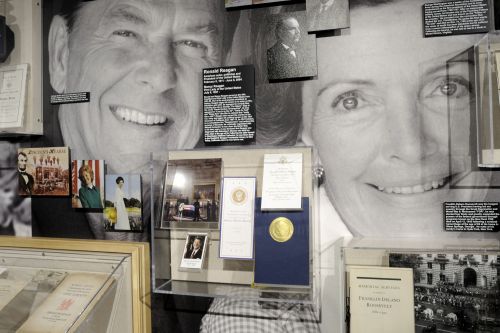 Exhibit featuring Ronald and Nancy Reagan, with photos, plaques, and memorabilia displayed on a wall.