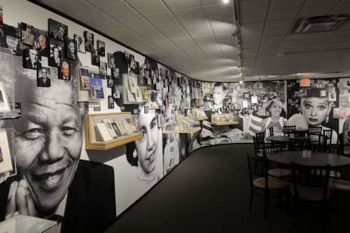 A gallery wall featuring black-and-white portraits of famous figures, with tables and chairs in the foreground.