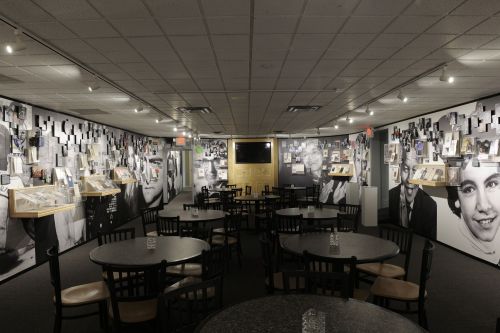 A dimly lit room with black and white photos on the walls and tables arranged for dining.