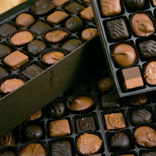 A variety of assorted chocolates in a black box, featuring different shapes and textures.