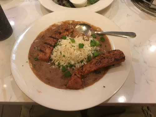 A plate of rice topped with grilled salmon and a rich brown sauce, garnished with green onions.