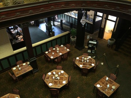 Aerial view of a restaurant with octagonal tables set for dining, featuring elegant decor and a chandelier.
