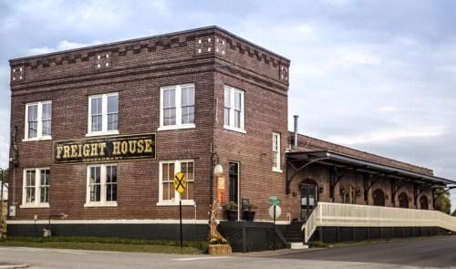 Historic brick building with "Freight House" sign, featuring large windows and a loading dock.