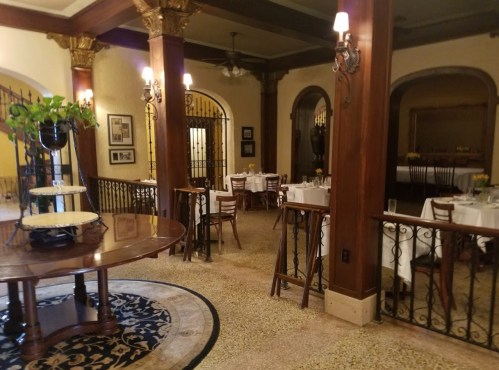 Elegant restaurant interior with wooden accents, round tables, and soft lighting, featuring a cozy atmosphere.