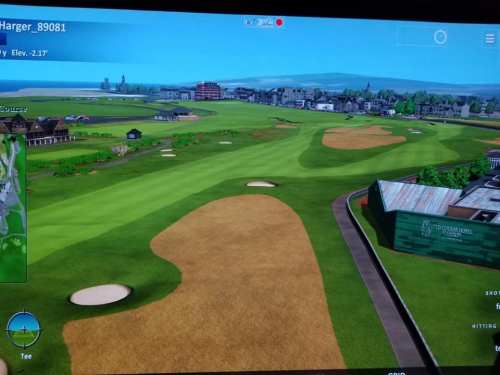 A scenic golf course view with sand traps, lush greens, and a coastal backdrop, displayed on a digital screen.