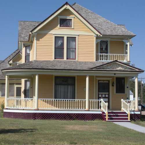 A large yellow Victorian-style house with a porch, multiple windows, and a gabled roof.