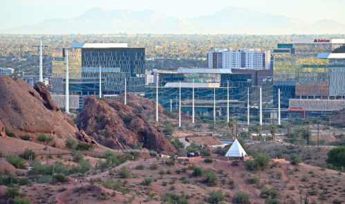 View of urban buildings and mountains in the background, with rocky terrain in the foreground.