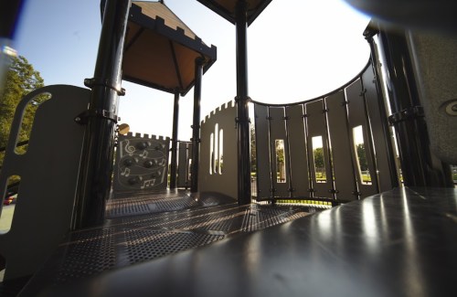 A playground structure with slides and climbing features, set against a clear blue sky.