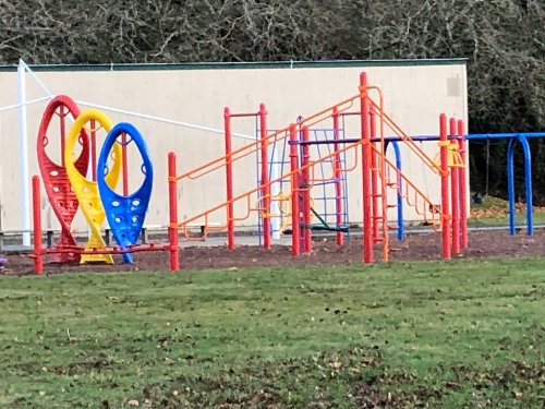 Colorful playground equipment with slides and climbing structures set on grassy ground.