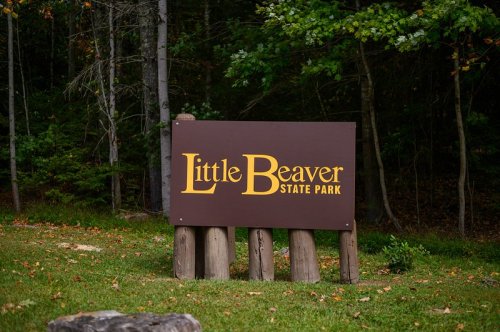 Sign for Little Beaver State Park surrounded by trees and greenery.