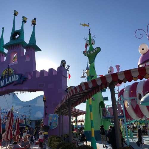 Colorful amusement park entrance with whimsical structures and bright blue sky. Fun atmosphere with playful designs.