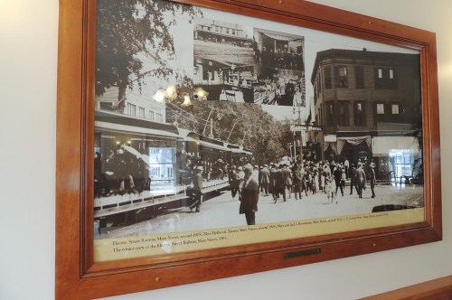 Historic black-and-white photo collage of a busy street scene with people and vintage streetcars.