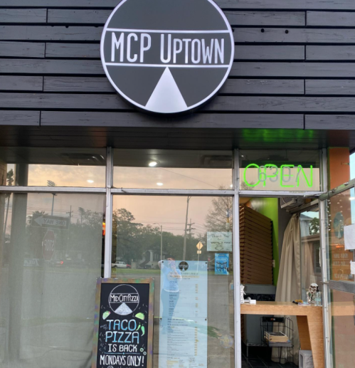 Exterior of MCP Uptown restaurant with an open sign and a chalkboard advertising Taco Pizza on Mondays.