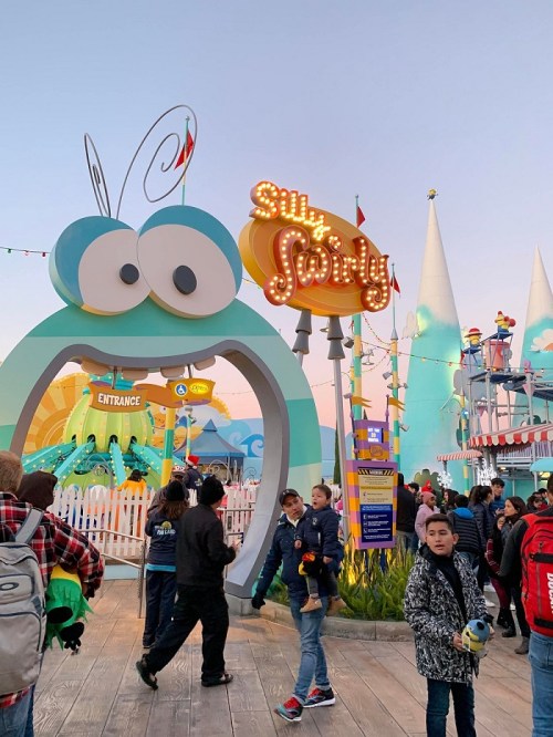 Colorful entrance to a whimsical amusement ride called "Silly Swirly," with people walking in and around the area.