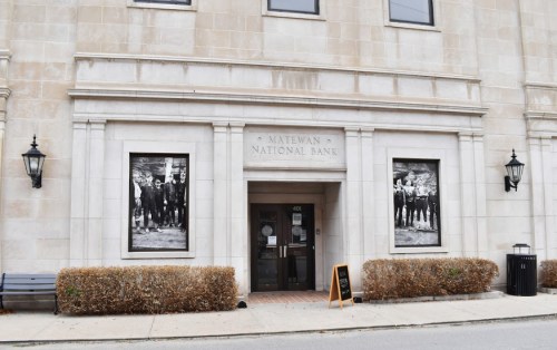 Historic Matewan National Bank building with black-and-white photos displayed in windows and a sign outside.