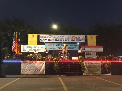 A stage with performers and banners at a nighttime event in Houston, celebrating the Vietnamese community.