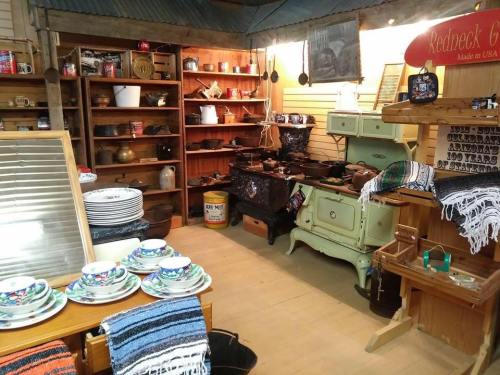 A cozy vintage shop interior with wooden shelves, antique kitchenware, and colorful tableware displayed on a table.