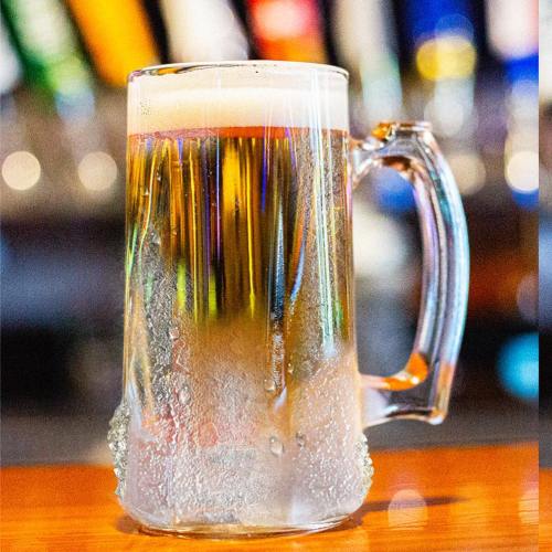 A frosty mug of beer with condensation, set against a blurred bar background.