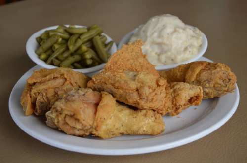 A plate of fried chicken with green beans and mashed potatoes with gravy on the side.