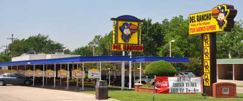 A colorful fast-food restaurant with a drive-in area, featuring a large sign and a promotional banner for family meals.