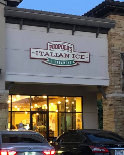 Sign for Puopolo's Italian Ice & Creamery on a storefront, with cars parked in front and warm lighting visible inside.