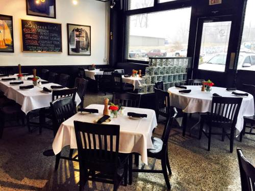 A cozy restaurant interior with white tablecloths, black chairs, and small flower arrangements on tables.
