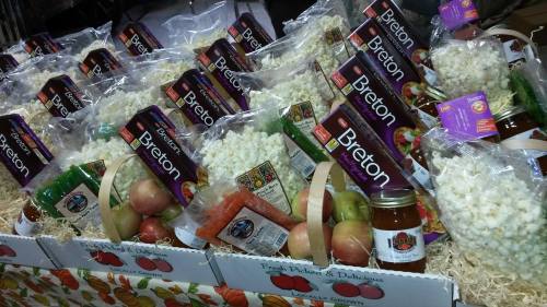 A display of gift baskets filled with Breton snacks, popcorn, apples, and jars of sauce, arranged on a festive table.