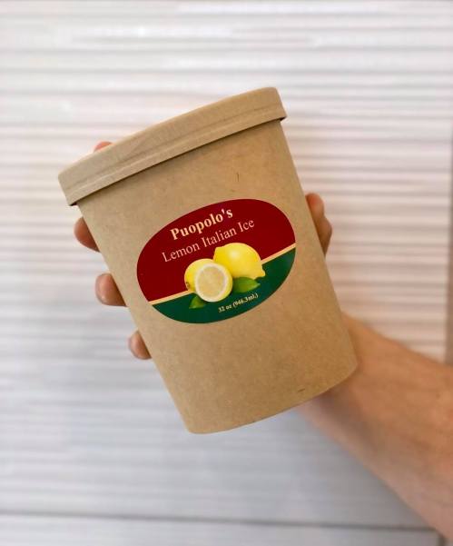 A hand holding a container of Puopolo's Lemon Italian Ice with a colorful label featuring a lemon.