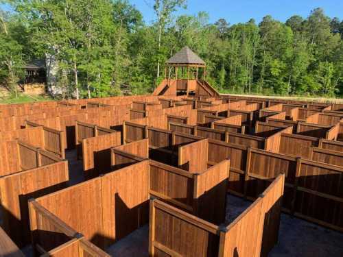 Aerial view of a large wooden maze surrounded by trees, with a lookout tower in the center.