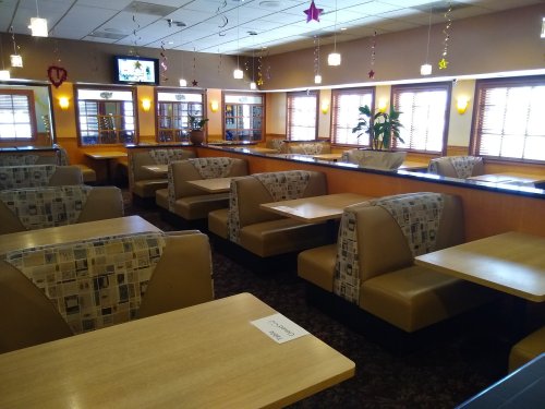 Interior of a restaurant featuring booths and tables, with warm lighting and decorative elements.