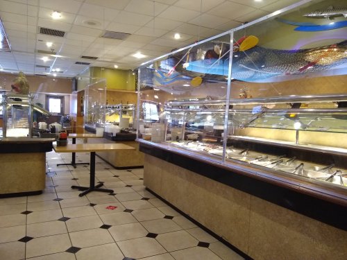 Interior of a buffet restaurant with glass partitions, empty food stations, and a table in the foreground.