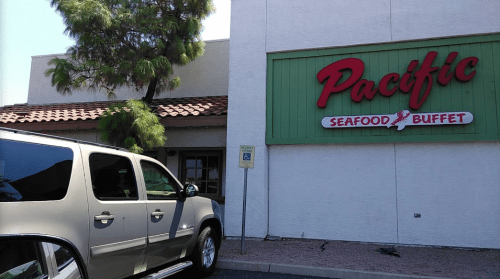 A gray SUV parked outside the Pacific Seafood Buffet restaurant with a green and red sign.
