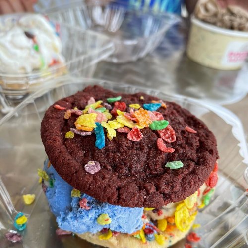 A colorful dessert featuring a red cookie topped with blue ice cream and sprinkled with vibrant cereal pieces.