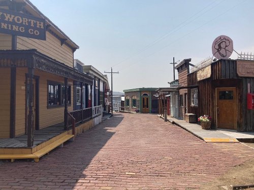 A historic street lined with wooden buildings, featuring brick pavement and a clear sky.