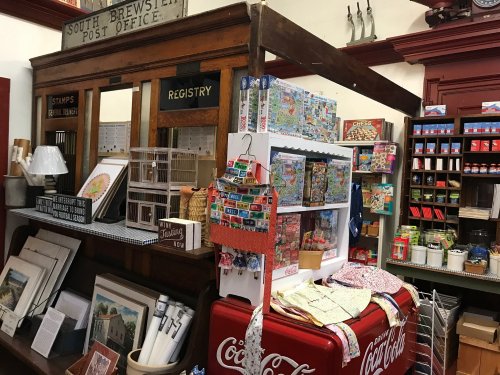 A vintage post office display featuring stamps, puzzles, and Coca-Cola memorabilia in a quaint shop setting.
