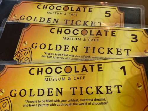 Three golden tickets for a chocolate museum and café, each with a unique number and a whimsical design.