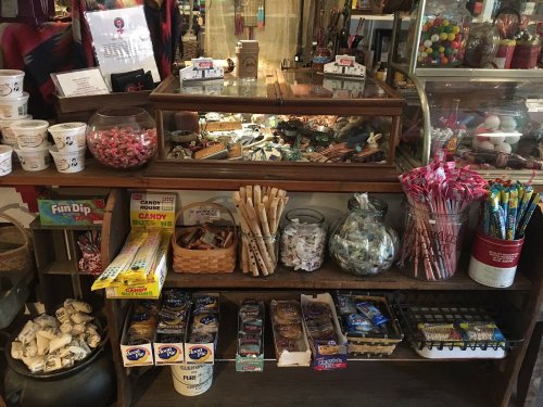 A vintage candy shop display featuring jars of sweets, candy boxes, and nostalgic treats on wooden shelves.