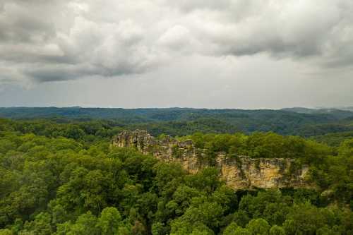 A scenic view of lush green hills and rocky cliffs under a cloudy sky.