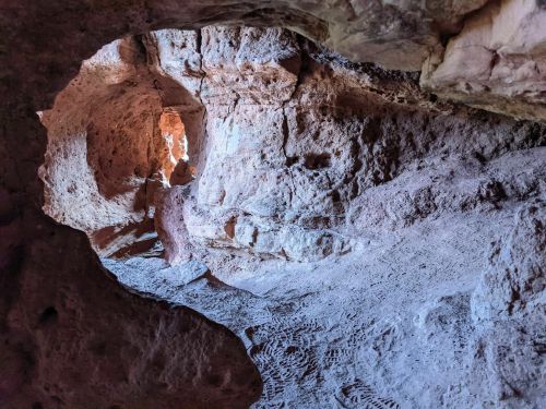 A rocky cave interior with textured walls and a light source illuminating the entrance.