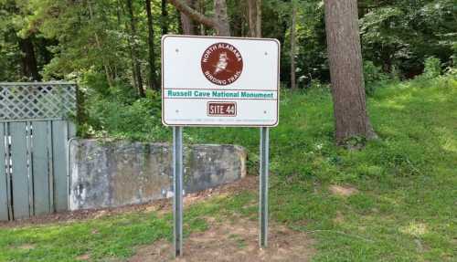 Sign for Russell Cave National Monument, indicating Site 44, surrounded by trees and greenery.