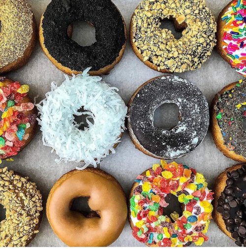 A variety of colorful donuts arranged in a grid, featuring toppings like sprinkles, coconut, and chocolate.