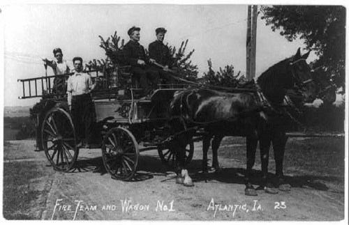 Black and white photo of a horse-drawn fire wagon with four men, labeled "Fire Team and Wagon No. 1, Atlantic, IA."