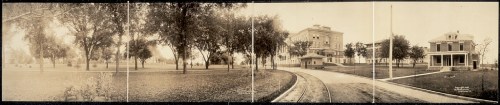 Panoramic view of a park with trees, buildings, and a pathway, captured in a vintage style.